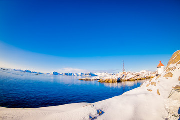 Outdoor view of the shore, all land covered with snow, with blue lake in snowy winter in the Arctic Circle