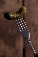 Cucumber on the fork in the broun background