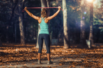 Woman Exercising With Elastic Band Outdoors in The Fall