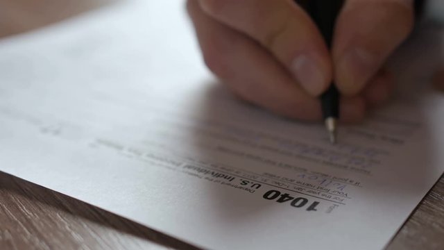 Man filling US tax form. tax form us business income office hand fill concept. Closeup.  Man Is Checking The Box Of Filing Status In The US Individual Income.  Tax Return Form 1040