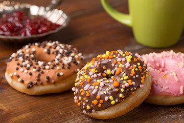 Coffee and donut. pink donut with a cup of tea on a dark wooden background. tasty breakfast.