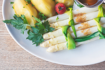 Frischer Spargel mit Kartoffeln und geschmolzener Butter auf einem weißen Teller im Restaurant serviert
