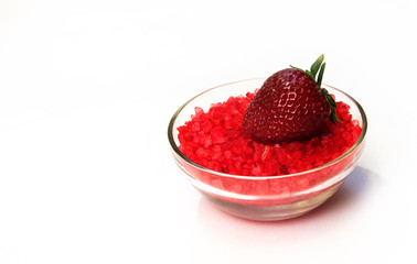 Glass bowl of red salt on white with strawberry