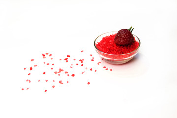 Glass bowl of red salt on white with strawberry