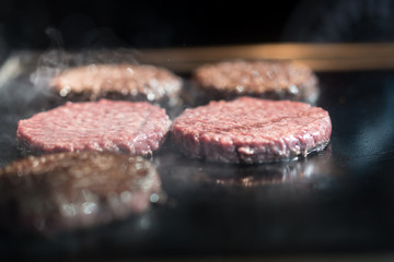 Hamburger cutlet frying on pan.Natural meet loaf pieces cooking in the kitchen.Burger sandwich meat being cooked with a lot of white smoke from a fat and oil.