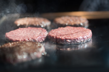 Hamburger cutlet frying on pan.Natural meet loaf pieces cooking in the kitchen.Burger sandwich meat being cooked with a lot of white smoke from a fat and oil.