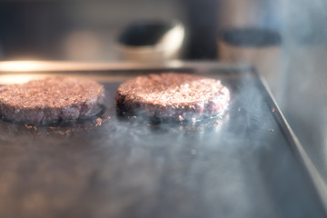 Hamburger cutlet frying on pan.Natural meet loaf pieces cooking in the kitchen.Burger sandwich meat being cooked with a lot of white smoke from a fat and oil.
