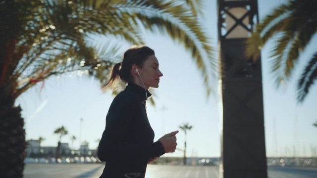 Young fitness woman jogging in the morning near the sea listening energetic music in earphones, Motivation Sport Healthy Lifestyle, slow motion