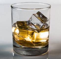 Whiskey in glass with ice cubes with white background