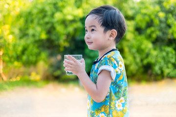 Asian Cute smile Boy drinking water for Healthy and Refreshing with green tree background.