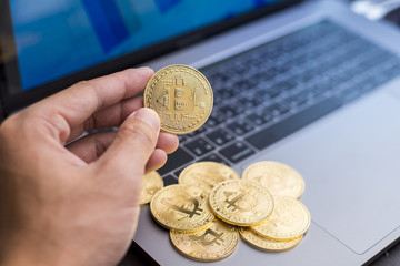 male hand holding  bitcoin on a laptop background.