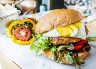 Beef cheese burger with french fried and vegetable on white paper
