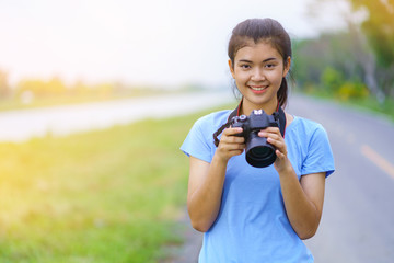 Portrait of beautiful girl in blue t-shirt and jeans smiling with a camera on hands