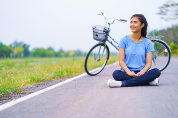 Girl with bike, Woman sitting on the road in the park and a bicycle