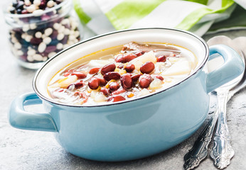Spinach and bean soup in a pot on concrete background. Selective focus, space for text. 