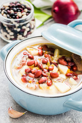Roasted garlic bean soup in a pot on concrete background. Selective focus, space for text. 
