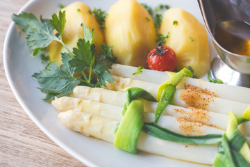 Bayerischer frischer Spargel mit Salzkartoffeln und geschmolzener Butter auf weisem Teller mit Deko, serviert im Restaurant