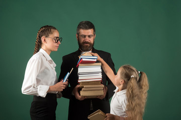 Teacher man and girls hold book pile at school. School time of sisters and father in library. Education in knowledge day. Literature lesson and reading grammar book. Back to school and home schooling