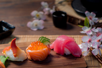 close up japanese foods, sushi set and tea pot set with sakura on the wooden table