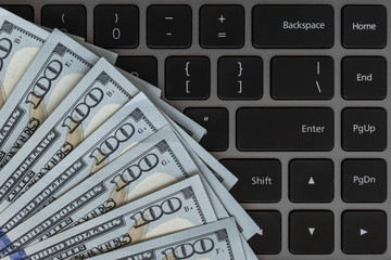 Dollars banknotes and black laptop keyboard as a background. American dollars money. Several...