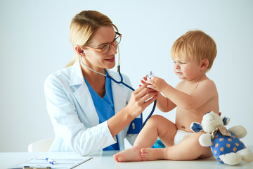 Female doctor is listening kid with a stethoscope in clinic