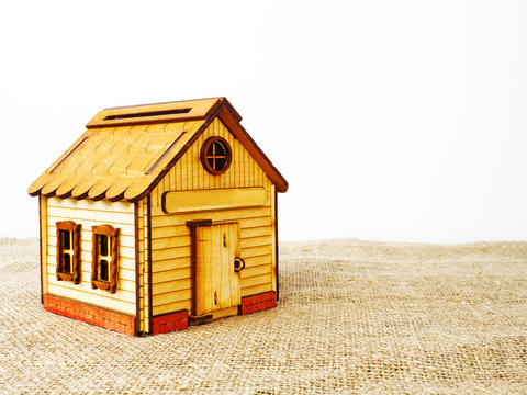 A toy wooden house on a background of burlap. The concept of an ecological habitat. Copy space