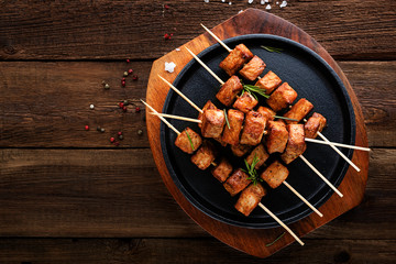 Grilled meat skewers, shish kebab on dark wooden background, top view