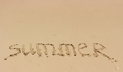 Hand inscription Summer on a wet sand in sunny day