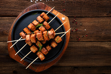 Grilled meat skewers, shish kebab on dark wooden background, top view