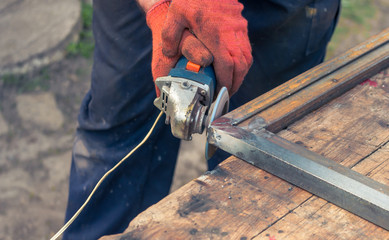 man is working with disk grinder for metal, man grinds metal, work with metal, work in a workshop