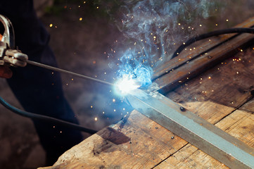 a man welds a metal with a welding machine, profession of welder, weld metal, man works with metal
