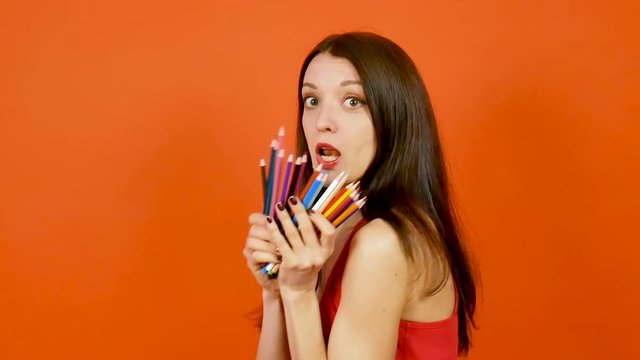 Young woman with color pencils on a orange background. Art design