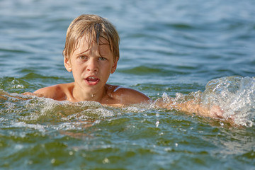 Happy little boy swimming in the river on summer weekend