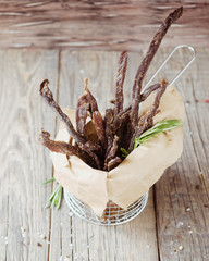 jerked meat, cow, deer, wild beast or biltong in kraft paper bowls on a rustic table, selective...