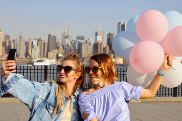 Beautiful women taking a selfie with her smartphone on New York view