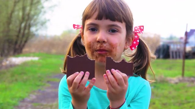 A sweet-toothed child eats chocolate. 