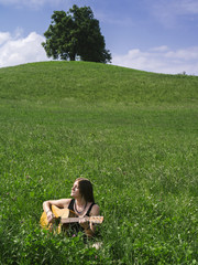 Woman playing guitar in large field