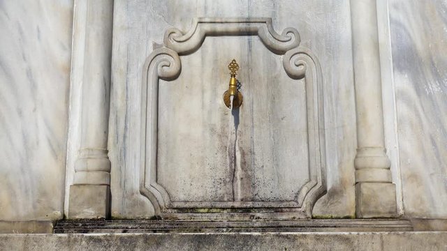 A tap with water on a marble wall.