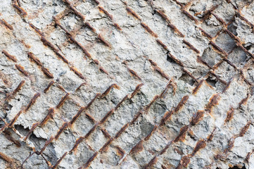 Textured background of an old concrete wall with a rusty outwardly extending reinforced armature....