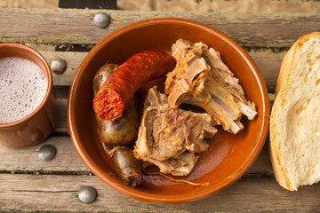 Cecina de Chivo. Plato tipico y tradicional de  carne curada y cocida de chivo ( cria de cabra) de Vegacervera en León España. En cazuela de barro y acompañada de chorizo y morcilla, pan y  vino © Siur