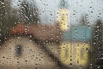 Rain drops on window glass with house and church in background