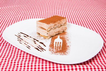 Delicious world famous Tiramisu cake on a white plate with decoration
