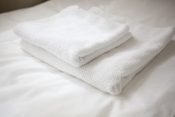 Two white towels on a white sheet
