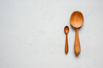 Wooden hand-made spoons lay on a gray background.