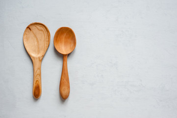 Two large wooden handmade spoons lay on a gray background.