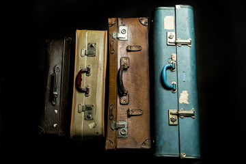 four old suitcases on a black background