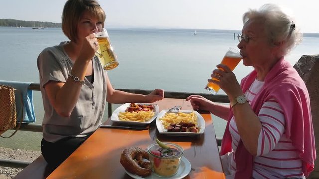 Seniorin mit junger Frau im Biergarten
