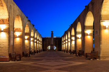 Fototapeta na wymiar Valletta, Malta, Upper Barrakka Gardens. Illuminated stone arches in the evening