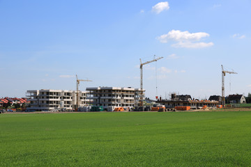 Apartamentowce, ogromne dźwigi na budowie osiedla mieszkaniowego w Opolu.