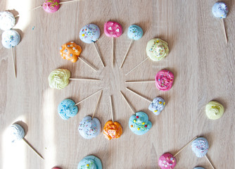 clock shaped meringues. meringue on candy stick. colorful swiss or italian recipe sweets on wooden background in pastel shades. birthday party time and holiday celebration. flat lay dessert backdrop